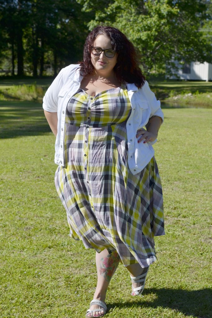 Maranda, a plus size woman, stands with hands on hips wearing a plaid Torrid dress with white denim jacket for Outfit of the Day.
