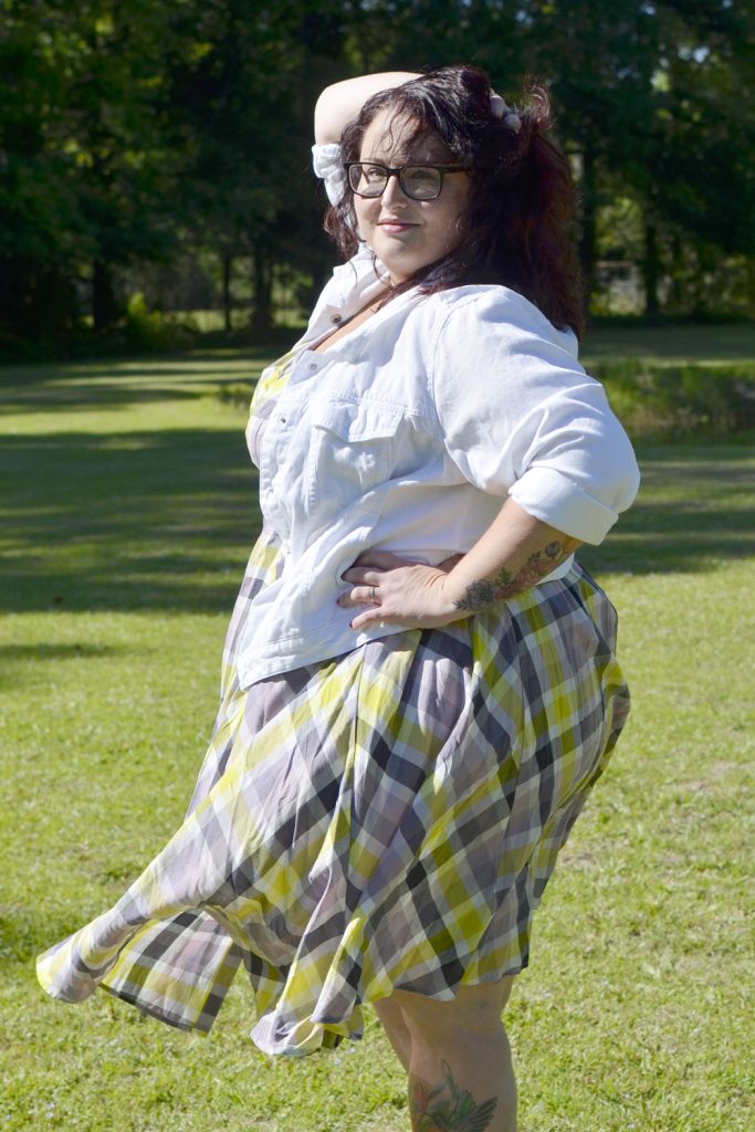 Side view of Maranda, a plus size woman, modeling Outfit of the Day wearing a plaid Torrid dress with white denim jacket.