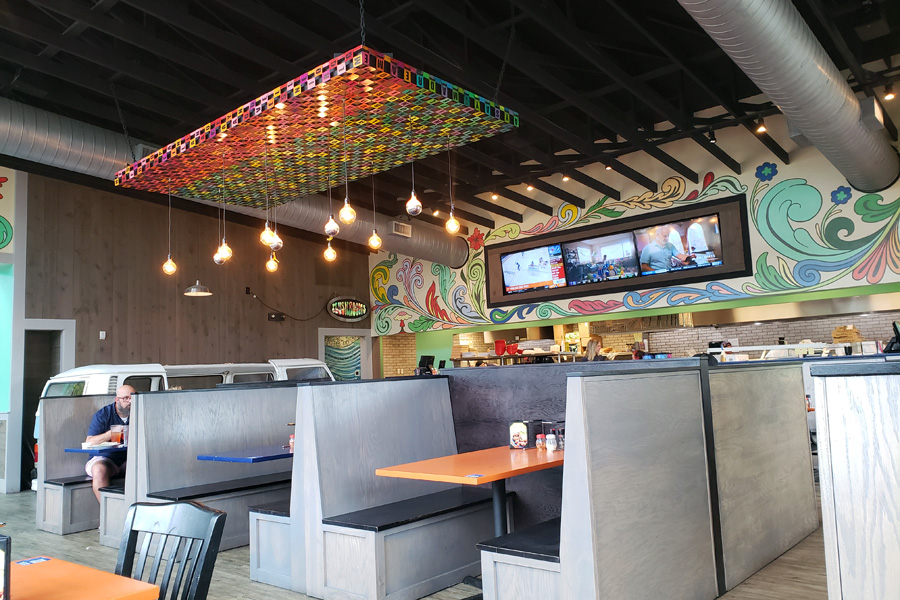 Interior view of Mellow Mushroom's main dining area, including booths, hand-painted floral wall art, and colorful lighting fixture.