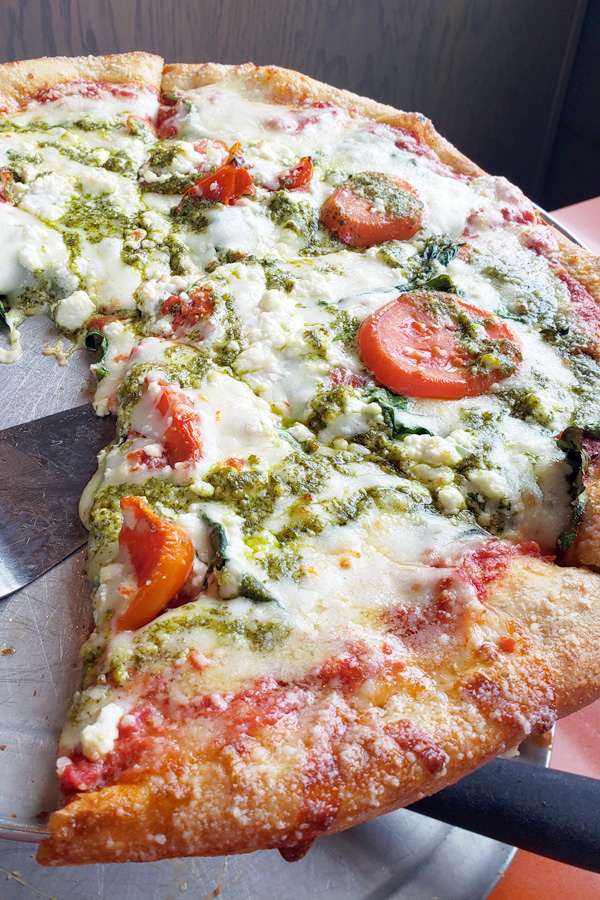 Mellow Mushroom signature pizza, Kosmic Karma, featuring spinach, feta, pesto, roasted and fresh tomatoes.