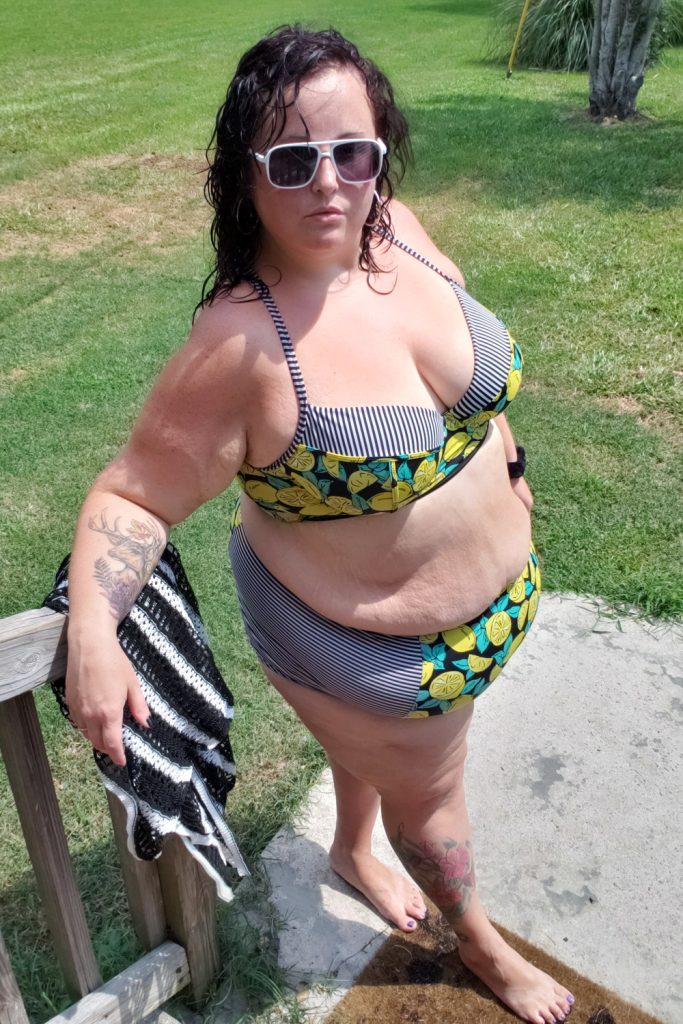 Maranda, a plus size woman, stands outdoors wearing a lemon print bikini set from Torrid.