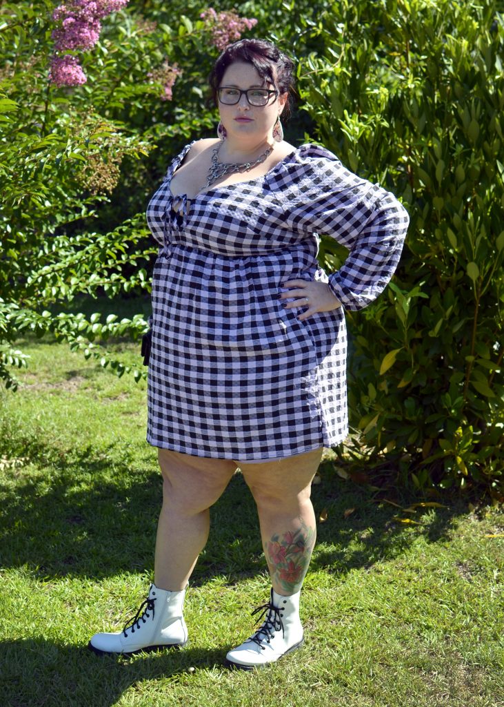 Maranda, a plus size woman, models a lavender and black plaid muse dress with white combat boots.