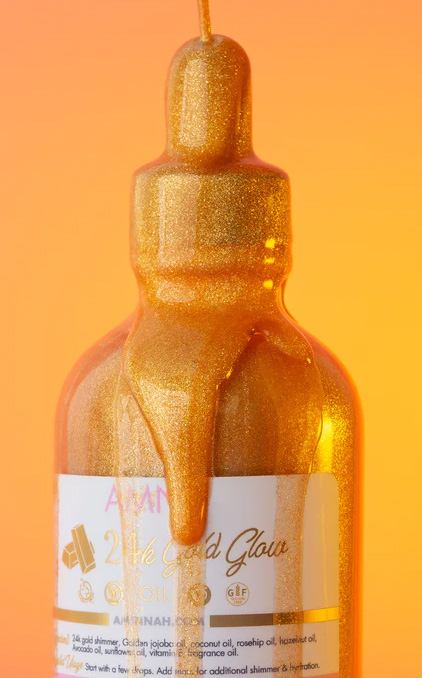 Stock photo of dripping 24k Gold Glow Body Oil by Aminnah Skin Care; gold shimmer liquid drips over glass bottle.