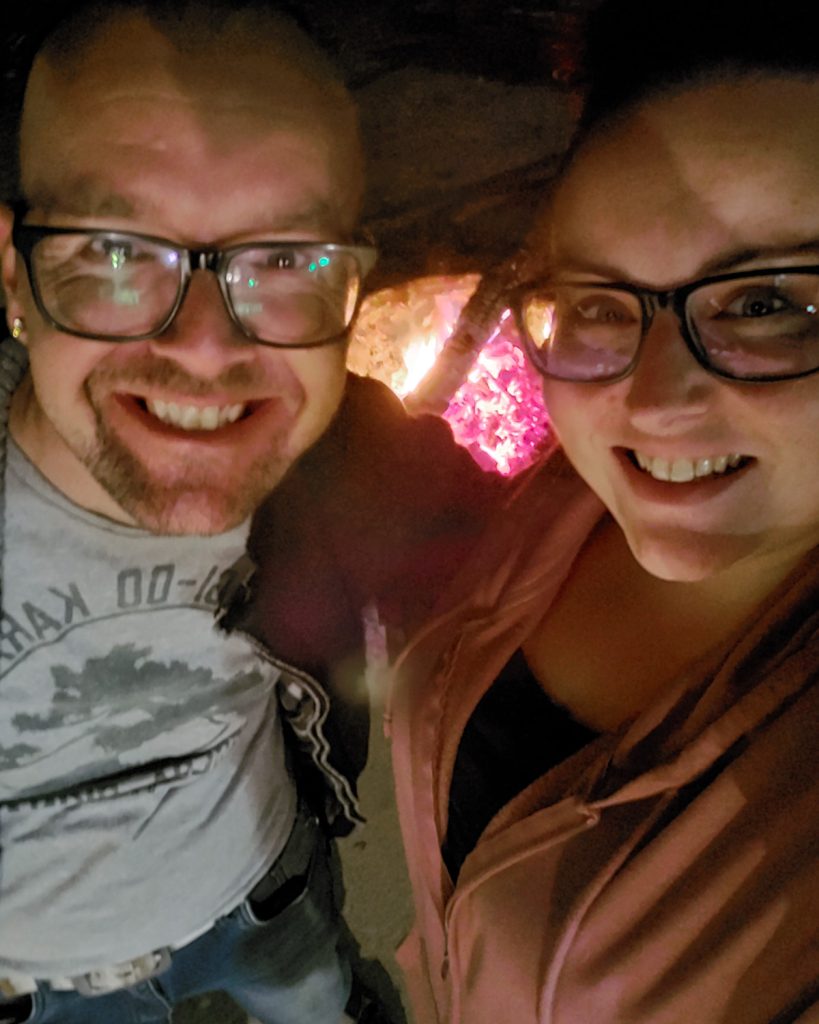 Candid selfie shot of Arnold and Maranda in front of glowing embers of the campfire.