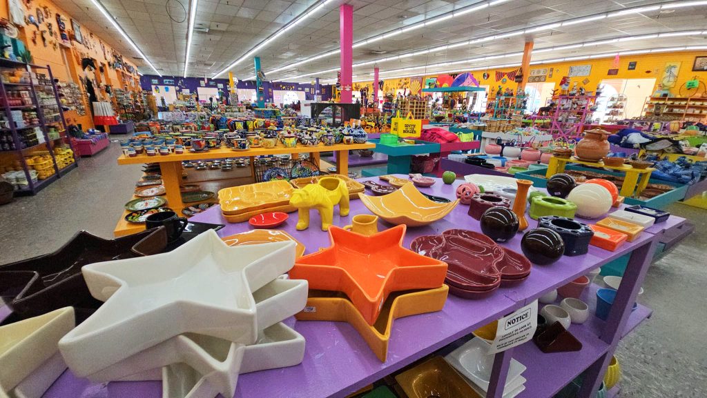 Colorful indoor shot looking toward the front of the Mexico Shop East gift store at South of the Border attraction. Pottery, dishware, and kitsch home decor items in various colors and styles.
