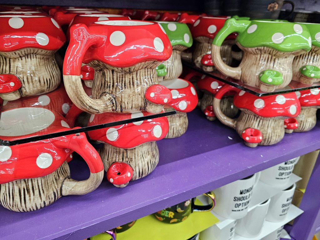 Glazed ceramic coffee mugs shaped like mushrooms with both red and green caps, with smaller mushrooms attached at the side as a pipe.