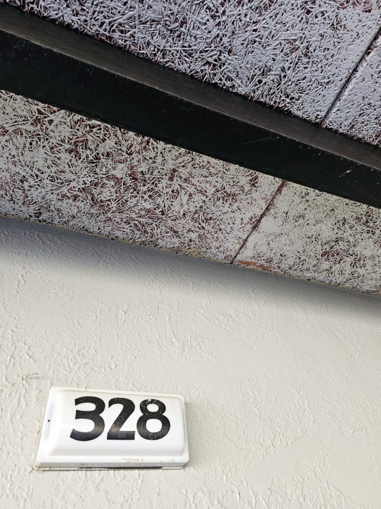 Artistic shot of the room number 328 under carport ceiling roof beam.