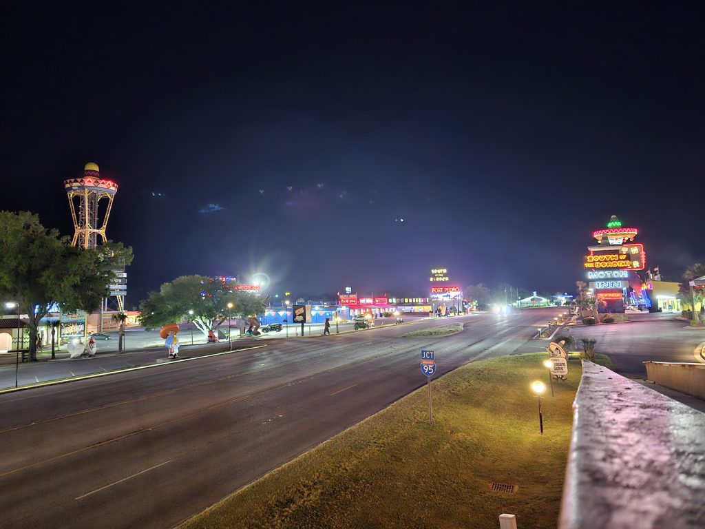 After dark view of South of the Border roadside attraction looking down the highway with bright lights and neon signs on either side of the road.