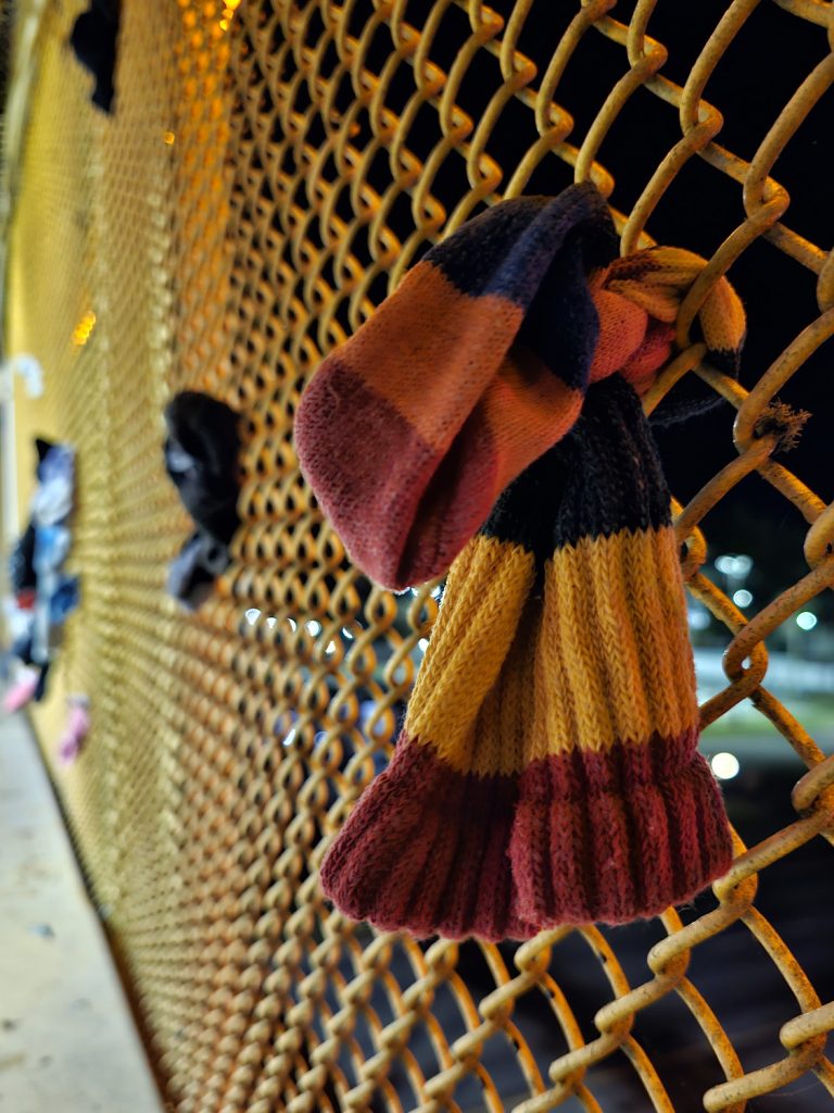 Close-up of a striped knit sock tied to the chain link enclosing walls of the old walkway at South of the Border roadside attraction.