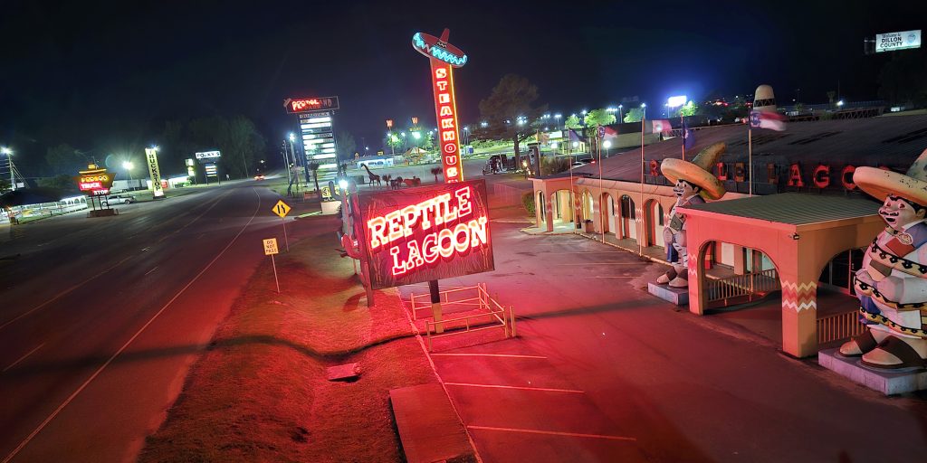 Nighttime shot of the Reptile Lagoon's red neon signage and parking lot within the South of the Border complex in Hamer, South Carolina.