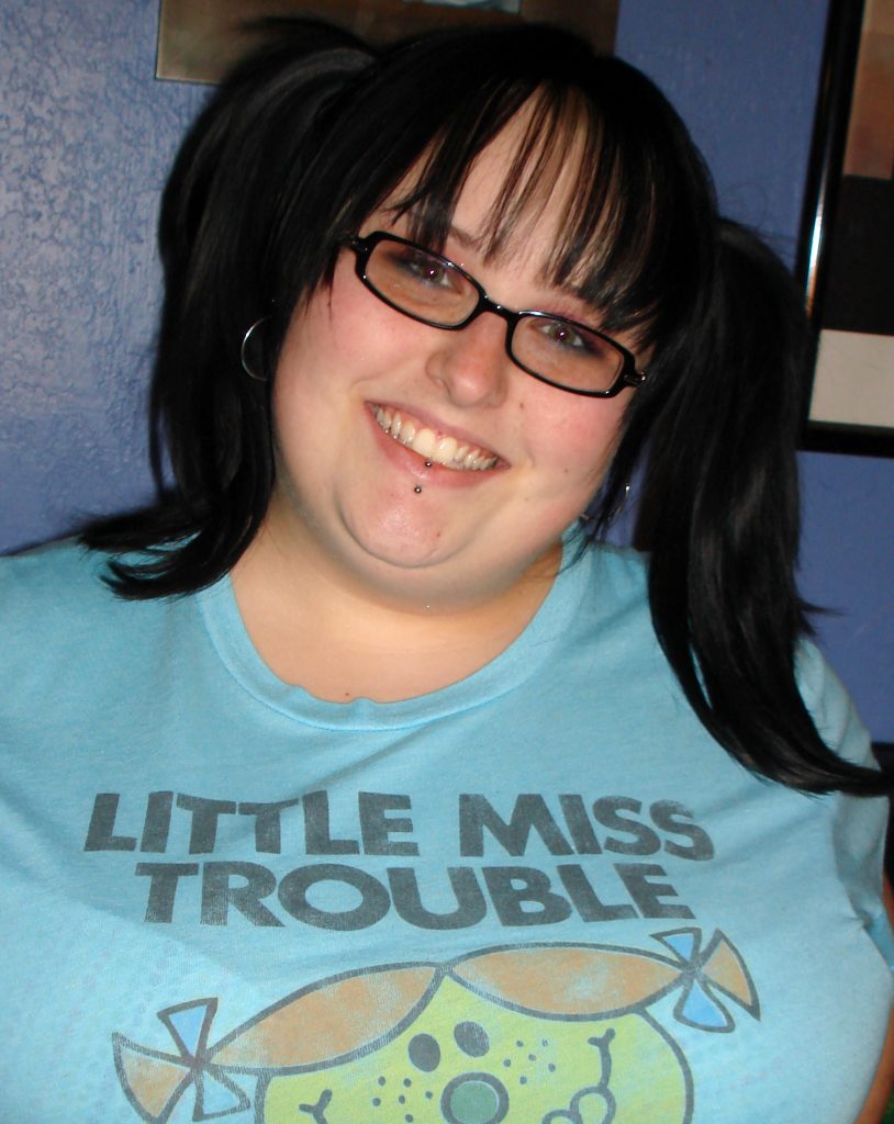 Maranda wears a blue Little Miss Trouble t-shirt with her hair up in pigtails.